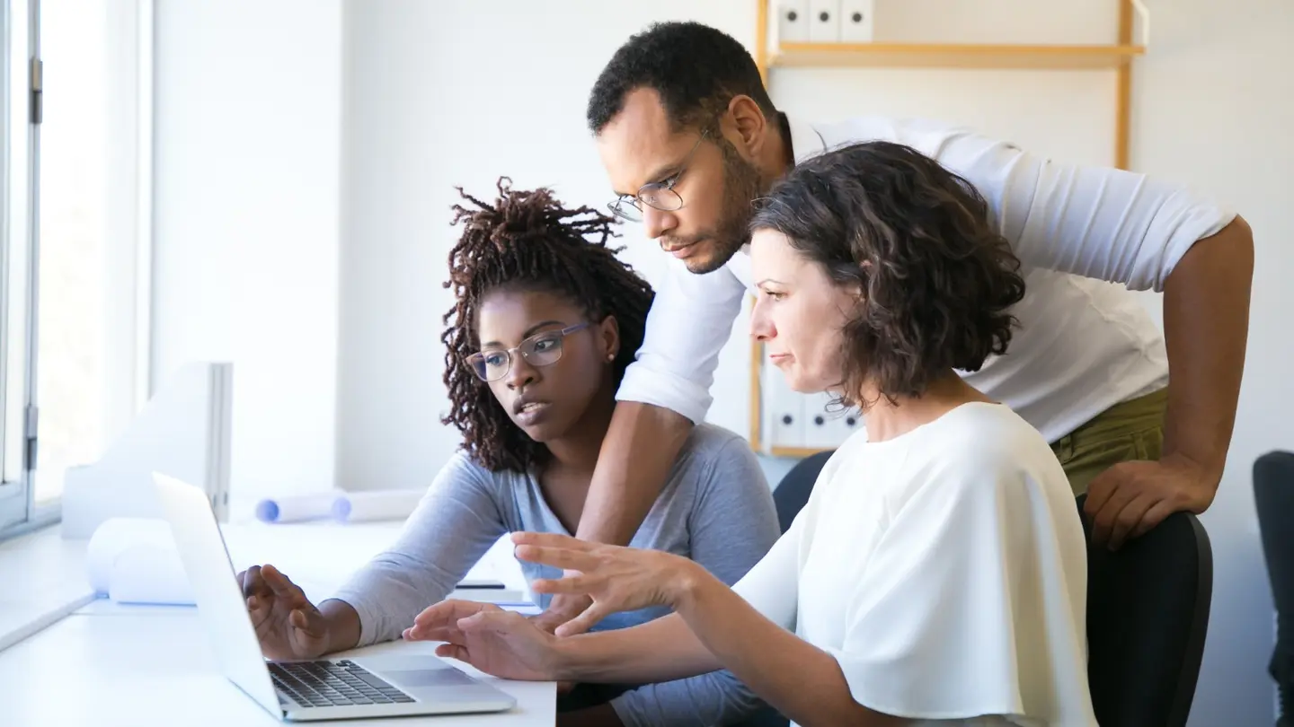 Employees reviewing cybersecurity information together on a laptop